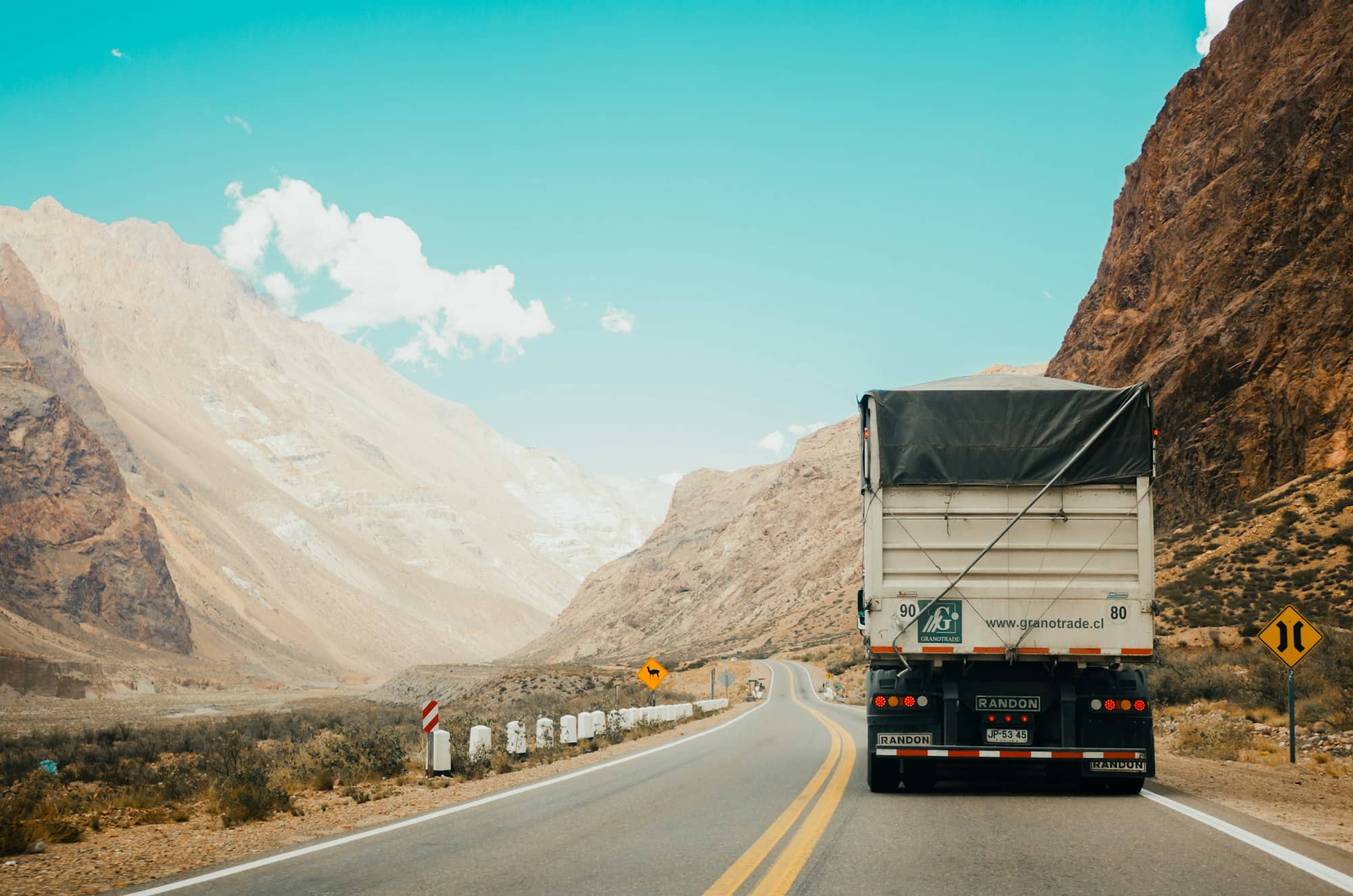 Camion semi-remorque avec chargement bâché sur une route de montagne