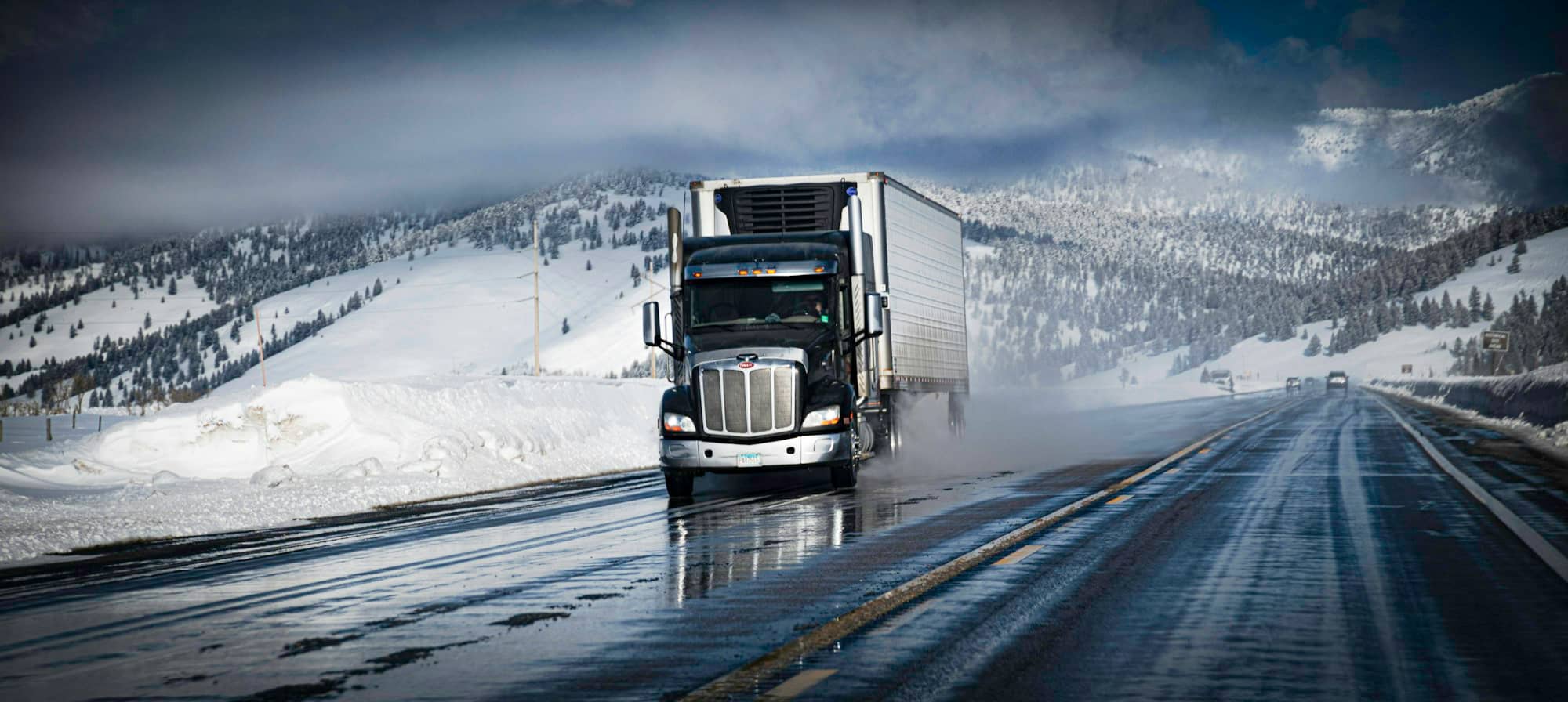 Camion semi-remorque roulant sur une route enneigée en hiver